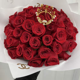 Bouquet of red roses wrapped in white paper with a gold crown topper