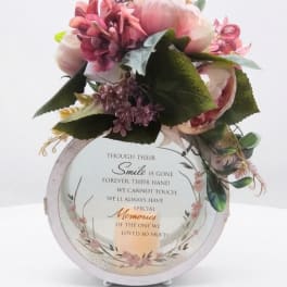 Pink floral arrangement on a memorial plaque with a candle graphic
