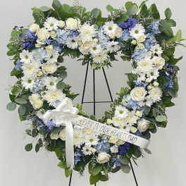 Heart-shaped floral wreath on a stand with a white ribbon