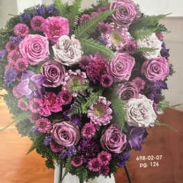 Heart-shaped bouquet of pink, purple, and white flowers on an easel