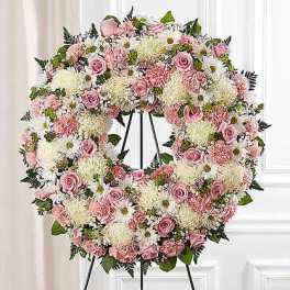 Pink and white floral wreath on a black stand