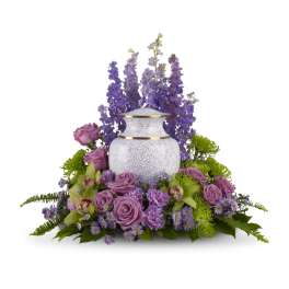 Purple floral arrangement around a white urn-shaped vase