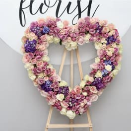 Heart-shaped floral arrangement of pink, white, and purple roses on an easel