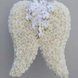 White rose floral arrangement shaped like angel wings with white orchids