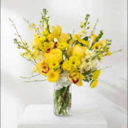 Yellow mixed flower arrangement in a clear glass vase