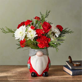 Red and white flowers arranged in a Santa-shaped vase