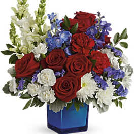 Red roses, white flowers, and blue blooms in a blue vase