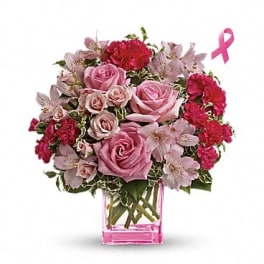 Pink roses and carnations in a clear square vase with a pink ribbon