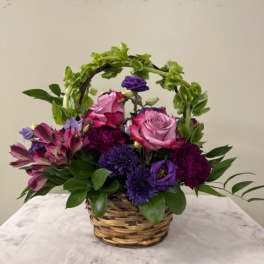 Basket arrangement of pink and purple flowers with greenery