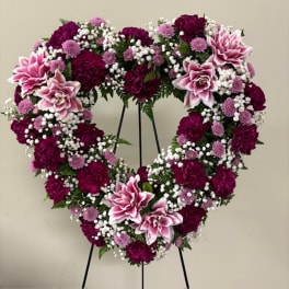 Heart-shaped floral wreath with pink and purple flowers on a stand