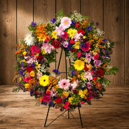 Colorful mixed flower wreath on a black stand
