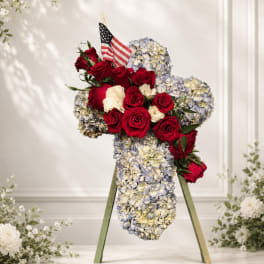Red roses and pale blue hydrangeas arranged in a cross on an easel