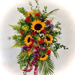 Tall floral spray with sunflowers, red carnations, purple daisies, and plaid ribbon