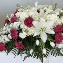 White lilies and pink carnations arranged in a casket spray