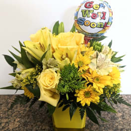 Yellow flower arrangement with a get well soon balloon in a vase
