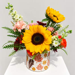 Sunflower and mixed flower arrangement in a leaf-patterned container