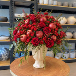 Red roses and apples arranged in a cream vase
