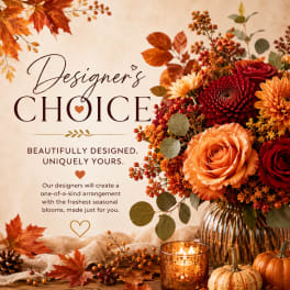 Autumn floral arrangement in a ribbed glass vase with a lit candle and small pumpkins