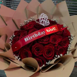 Bouquet of red roses wrapped in tan paper with a birthday ribbon