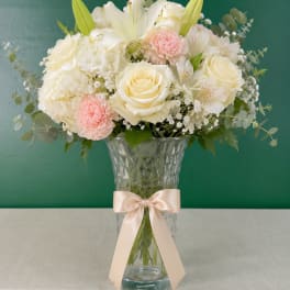 Cream and blush bouquet in a clear vase with a satin ribbon