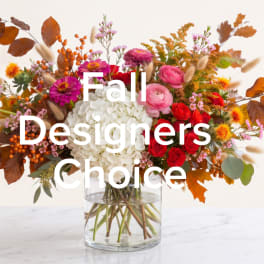 Mixed fall bouquet in a clear glass vase with white hydrangea and red, pink, and orange flowers
