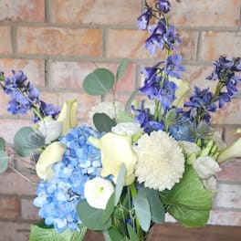Blue hydrangeas, white calla lilies, and white blooms in a vase