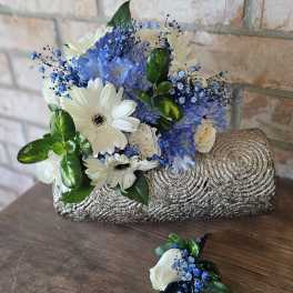 Blue and white bouquet with daisies and roses in a textured silver clutch