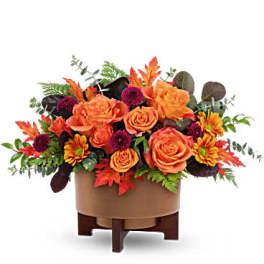 Orange roses and purple flowers in a low round container
