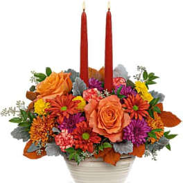 Flower arrangement with two red taper candles in a white bowl vase