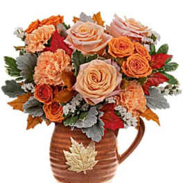 Bouquet of peach and orange roses in a brown ceramic pitcher vase