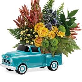 Yellow roses and mixed greenery arranged in a turquoise toy truck