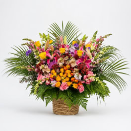 Large mixed flower arrangement in a woven basket with palm fronds