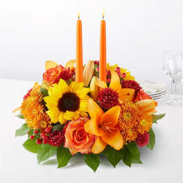 Orange candle centerpiece with sunflowers, roses, lilies, and mums