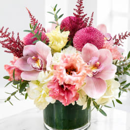 Pink orchids and carnations in a glass vase with red accents