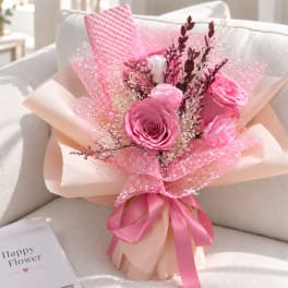 Pink rose bouquet wrapped in peach and pink paper with a satin ribbon