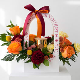 Flower gift box with orange roses, chrysanthemums, and a gold candle jar