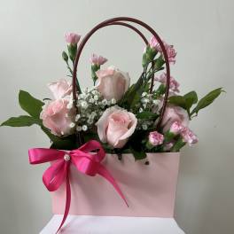 Pink roses and carnations in a pink gift bag with a ribbon bow