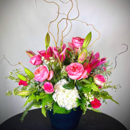 Pink roses and lilies arranged in a dark vase with white hydrangea
