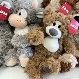 Plush stuffed animals with red gift tags are piled together