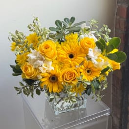 Yellow roses and daisies arranged in a clear glass vase