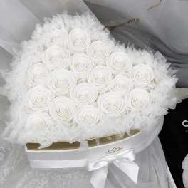 Round bouquet of white roses wrapped in sheer white tulle