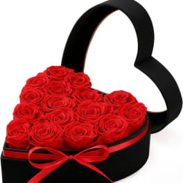 Heart-shaped box filled with red roses and tied with a red ribbon