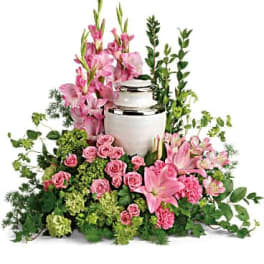 Pink flowers arranged around a white urn with greenery