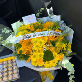 Yellow bouquet with daisies and roses, wrapped in white paper with a ribbon