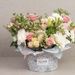 Pink and white flower arrangement in a patterned box