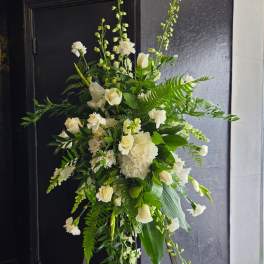 Tall white floral standing arrangement with mixed greenery