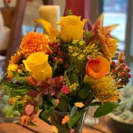 Yellow and orange floral arrangement in a clear glass vase