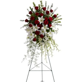 Standing floral spray with red roses and white lilies on an easel