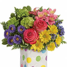 Colorful bouquet of roses, daisies, and purple flowers in a polka-dot vase