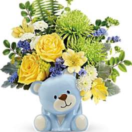 Yellow and white flowers arranged in a blue teddy bear container